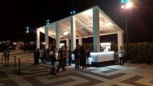 Side view Crowds gather at mobile food cart and bar kiosk on sloped ground at the Greek Theater