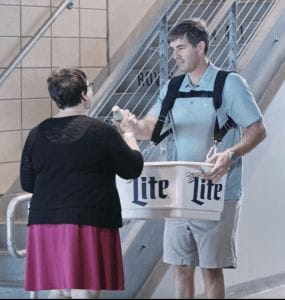 A man uses a hawking tray to sell beer at a stadium
